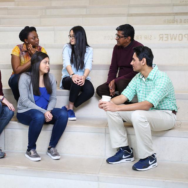 students sit on the library steps surrounded by different languages