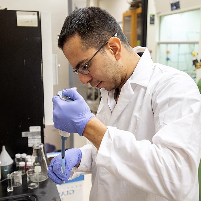 A graduate student carefully meters material into a test tube